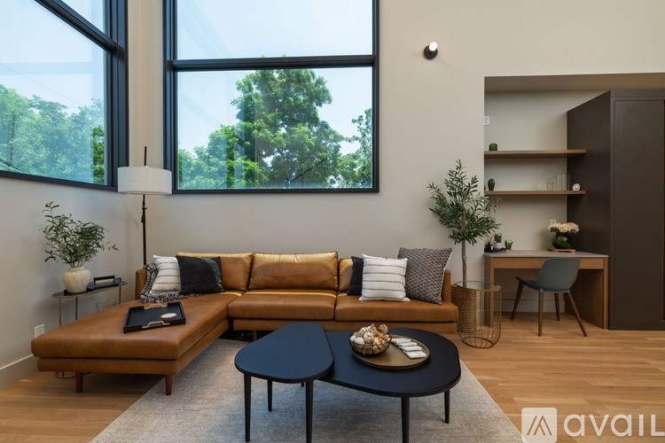 A living room with a brown leather couch, a black coffee table, and a large window.