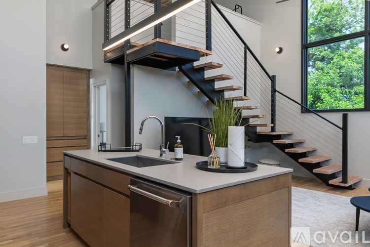 A kitchen with a staircase in the background.