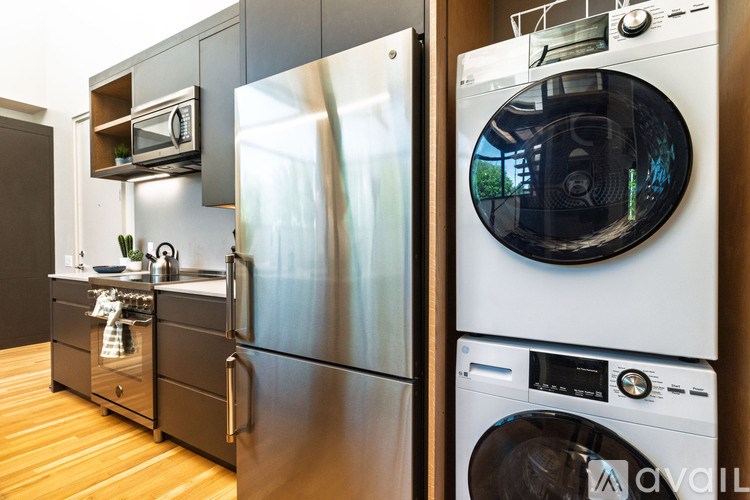 A modern kitchen with a stainless steel refrigerator and a washing machine.