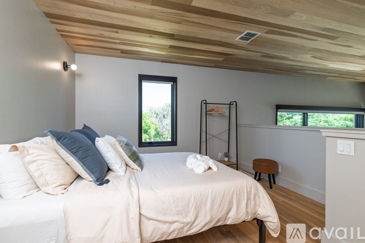 A bedroom with a bed, pillows, a chair, and a window.