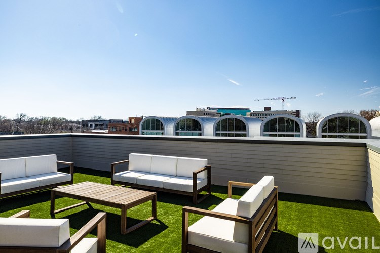 A patio with white couches and wooden tables.