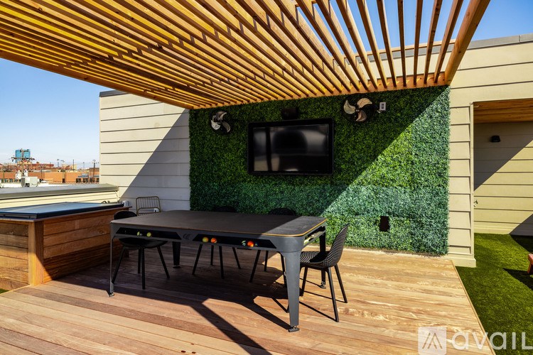 A wooden deck with a table and chairs and a TV on a green wall.