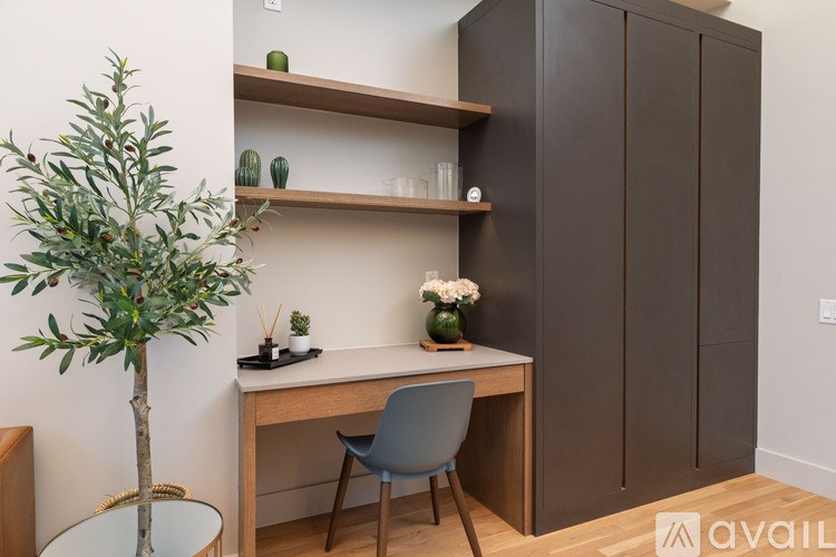 A room with a desk, chair, and a tree.