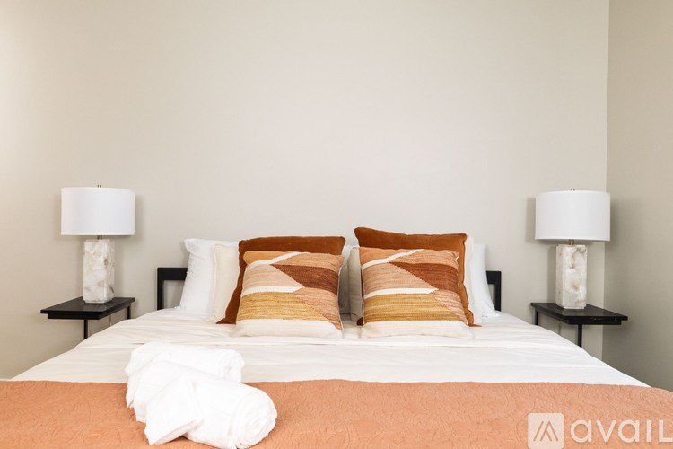 A bed with a white comforter and two pillows with orange and white stripes.