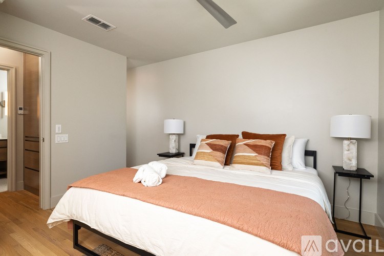 A bedroom with a bed, two lamps, and a towel on the bed.