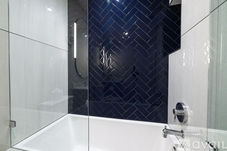 A modern bathroom with a white bathtub and a black tiled wall.