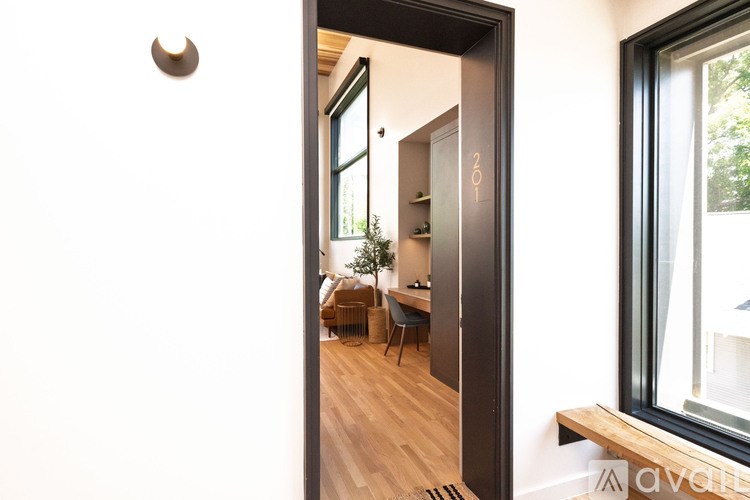 A modern interior with a wooden floor and a glass door leading to a balcony.