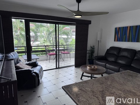 A living room with a black couch and a ceiling fan.