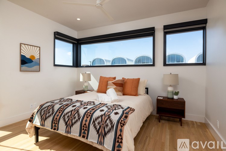 A bedroom with a bed, two lamps, and a painting on the wall.
