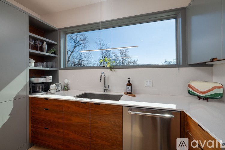 A kitchen with a stainless steel dishwasher and wooden cabinets.