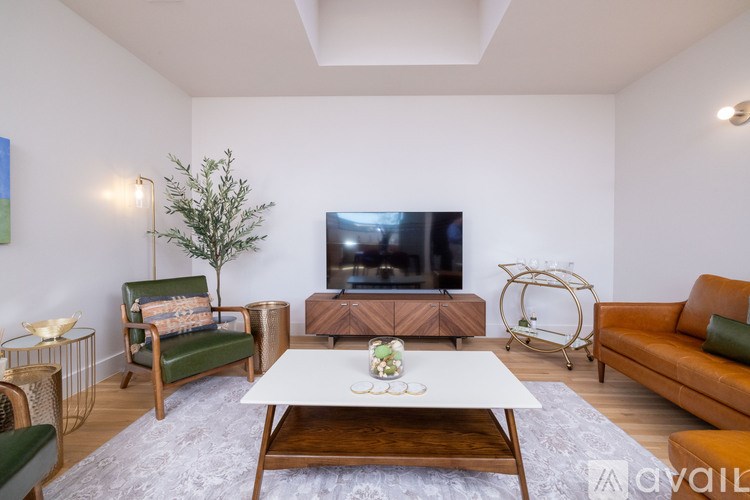 A living room with a white couch, a green chair, a wooden coffee table, and a television.