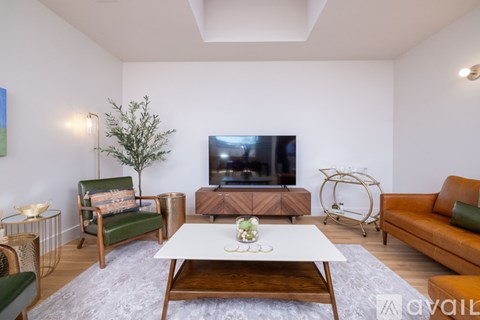 A living room with a white couch, a green chair, a wooden coffee table, and a television.