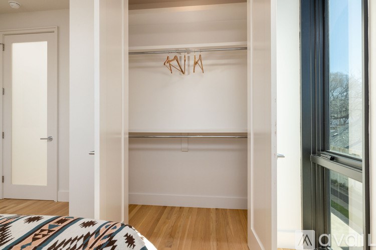 A white closet with a coat hanger and a window.
