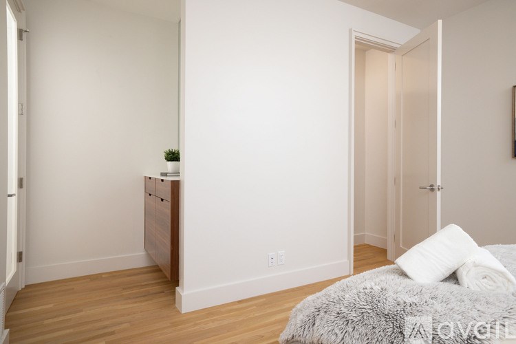 A bedroom with a bed, nightstand, and a plant on the nightstand.