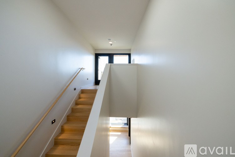 A long hallway with a staircase on the left and a door on the right.