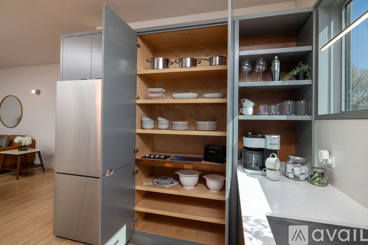 A modern kitchen with a large open refrigerator and wooden shelves.
