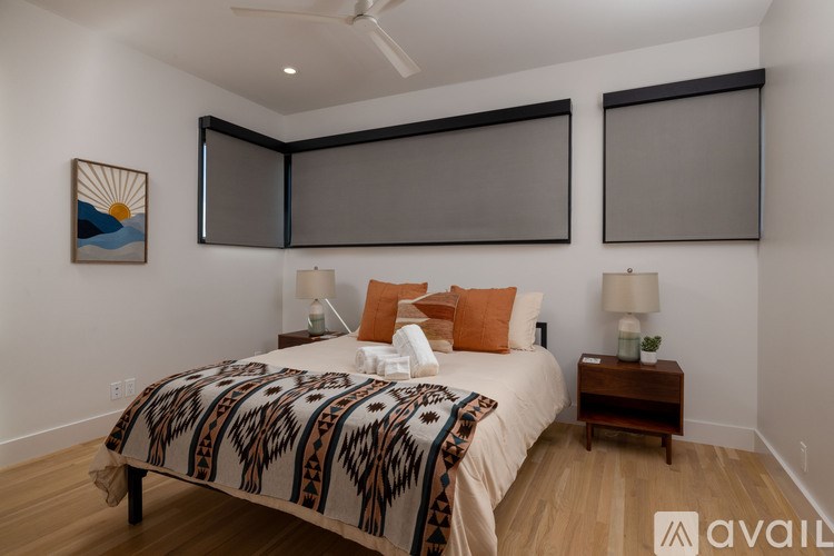 A bedroom with a bed, two lamps, and a painting on the wall.