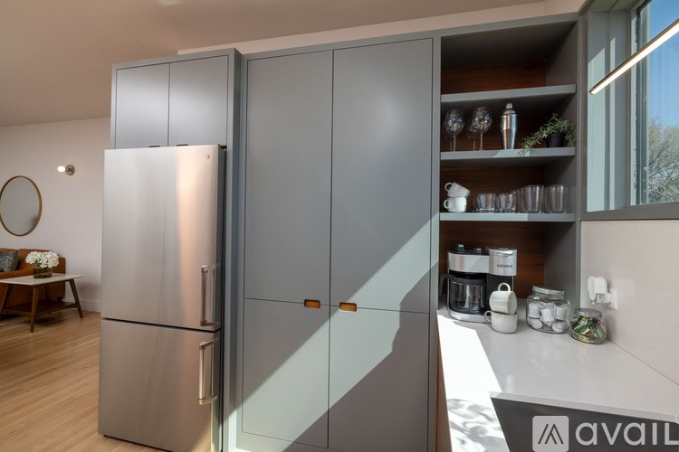 A modern kitchen with a stainless steel refrigerator and wooden flooring.