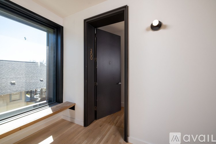 A black door with a handle is in a white room with a window.