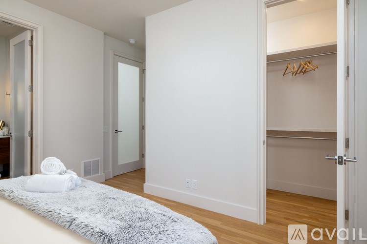 A bedroom with a bed, a rug, and a closet with clothes hanging.