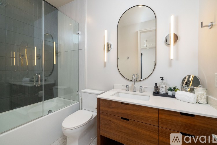 A bathroom with a toilet, sink, mirror, and a glass shower stall.