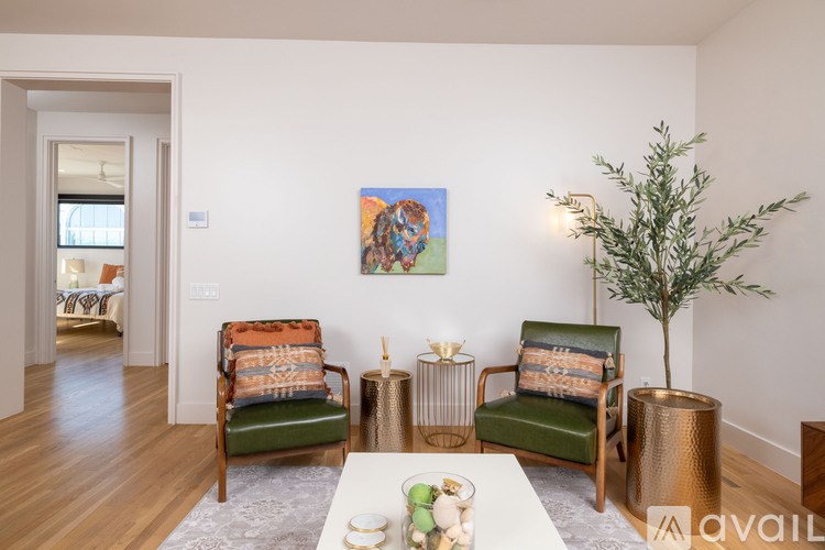 A living room with two chairs, a table, and a painting on the wall.