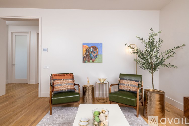 A living room with two chairs, a table, and a painting on the wall.