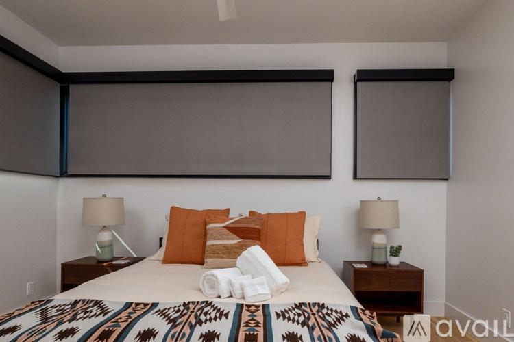 A bedroom with a bed, two lamps, and a wall-mounted TV.