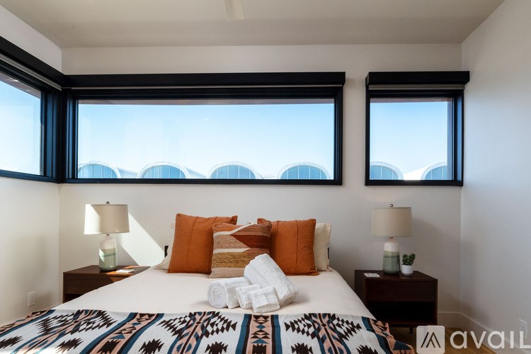 A bedroom with a large bed and two windows.