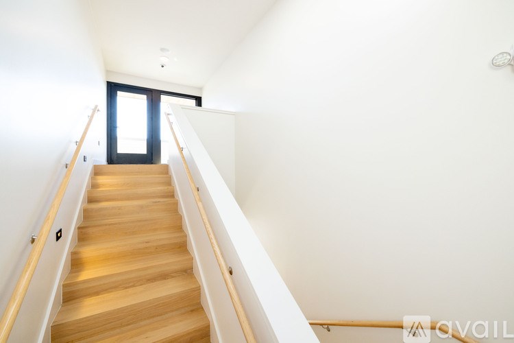 A wooden staircase with a white railing leads to a black door.