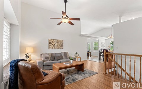 A living room with a brown leather chair and a ceiling fan.