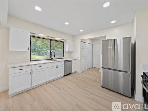 A kitchen with white cabinets and a stainless steel refrigerator.