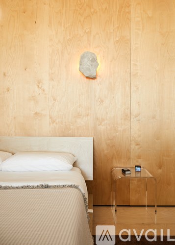 A bed with a white pillow and a small table with a phone on it.