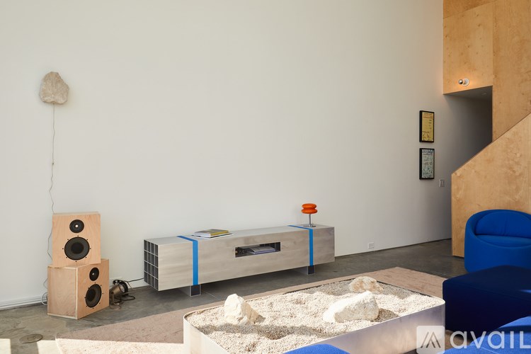 A room with a speaker, a table with a blue tape and a chair.