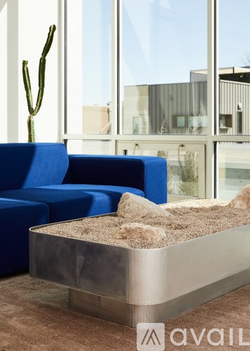 A blue sofa and a sand table in a room with a cactus.