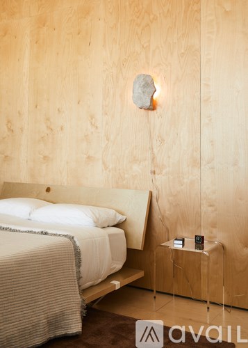 A bedroom with a bed, nightstand, and a stone on the wall.