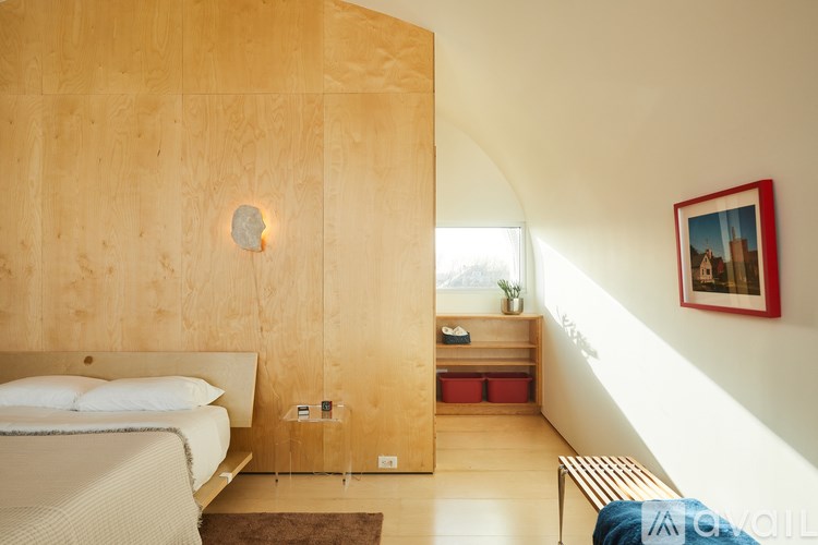 A bedroom with a bed, nightstand, and a window.