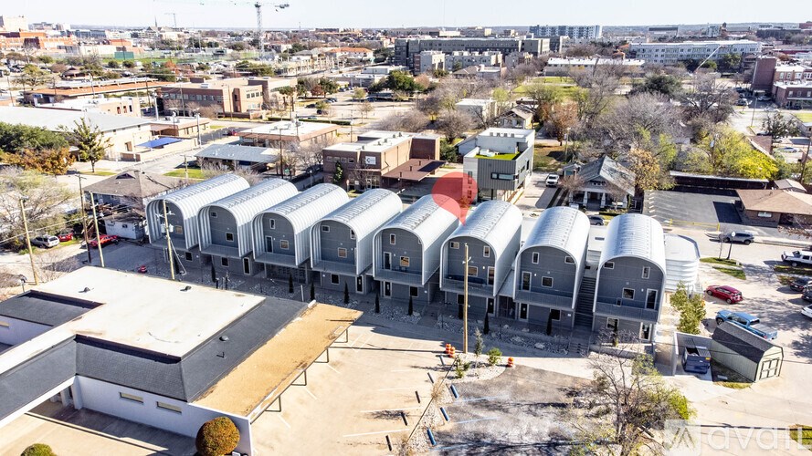 A large industrial building with a white roof and a red roofed building in the background.