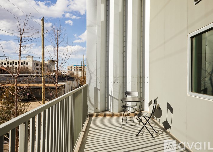 A balcony with a table and chairs overlooks a cityscape.