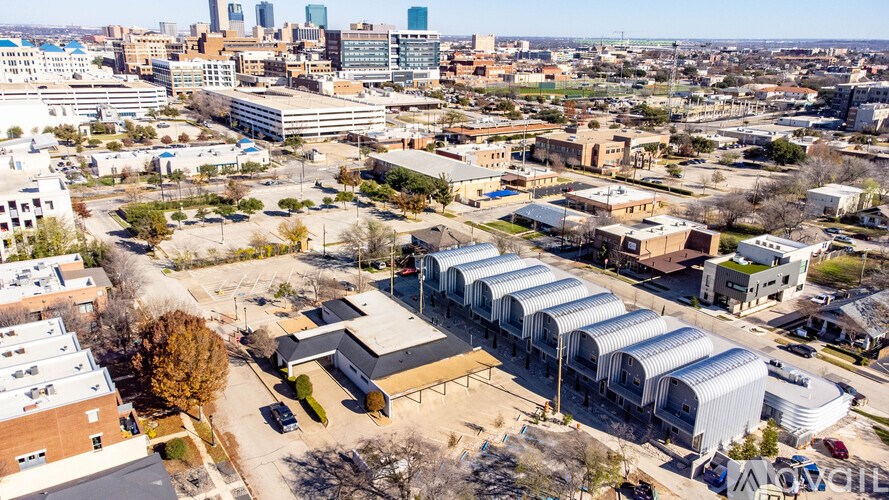 A large building with a curved roof is in the foreground of a cityscape.