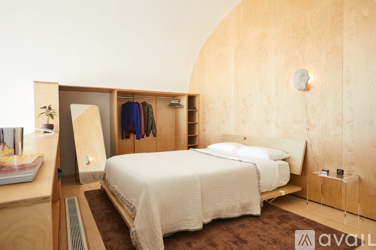 A bedroom with a bed, nightstand, and clothing rack.