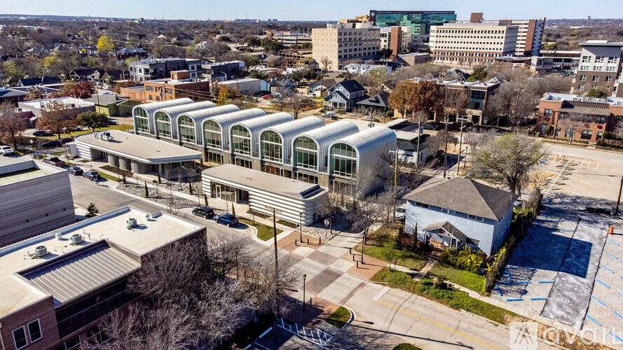 A large building with a curved glass facade is the focal point of this aerial cityscape.