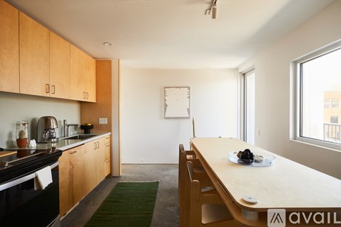 A kitchen with wooden cabinets and a long table with a bowl of fruit on it.