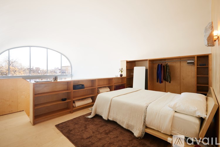 A bedroom with a large bed and a window overlooking a cityscape.
