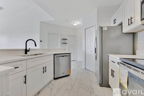 A kitchen with white cabinets and a marble floor.