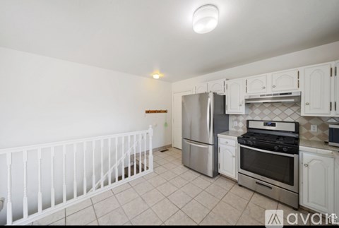 A kitchen with white cabinets and appliances, a stove, and a refrigerator.