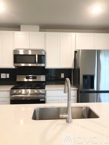 A kitchen with a stainless steel refrigerator and a stainless steel sink.