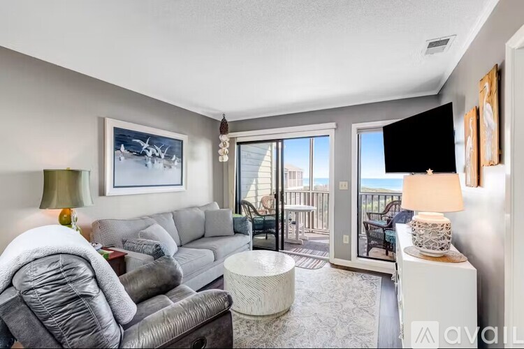 A living room with a grey couch and a painting of a plane on the wall.