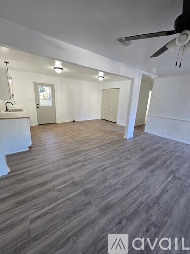 A spacious room with wooden flooring and a ceiling fan.