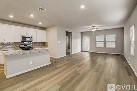 A spacious kitchen with a granite countertop and a microwave above it.